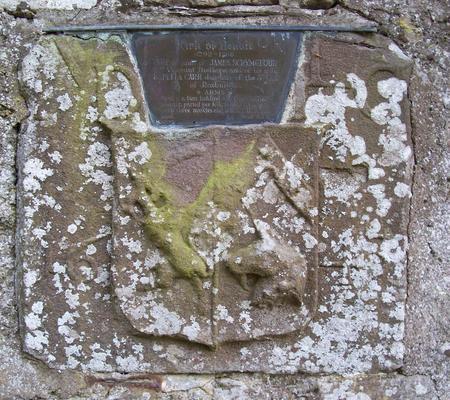 on the roadside wall of Benvie kirkyard. Arms of James Scrymgeour, 2nd viscount of Dudhope (a lion rampant wielding a scimitar) impaled with those of his spouse, Lady Isabella Kerr (or Carr), daughter of Sir Robert Kerr of Cessford, 1st earl of Roxburghe (on a chevron, three mullets, and a unicorn's head erased in base). Initials to dexter: IVD; to sinister, ILC. Date: 1643, which was the year of James's succession to the title. (The metal plaque above is inaccurate.)